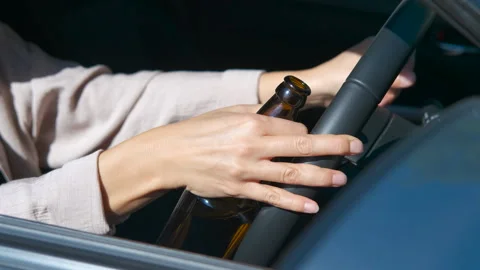Woman drinking beer while driving a car Stock Footage 344177237