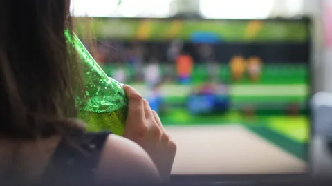 Woman Drinking Beer while Watching Sports on TV Video stock 151728930