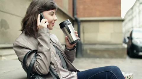 Woman drinking coffee and talking on cellphone, outdoors, steadicam shot HD Stock Footage