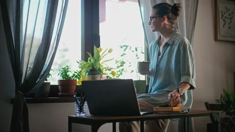 A woman drinking coffee and using a smartphone while working from home. Stock Footage 234394557