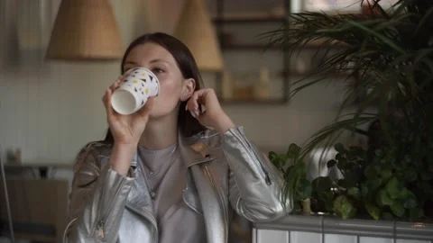 Woman drinking coffee in a cafe while waiting for a meeting with a partner Stock Footage 141427397