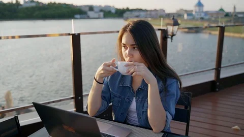Woman drinking coffee while using laptop at cafe Stock Footage 109634386
