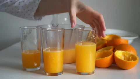 Woman is drinking fresh squeezing orange juice from electric juicer and glasses. 스톡 동영상 158531817