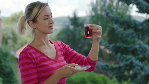 Woman is drinking a hot tea while watching the green view on the balcony. Video stock 140521617