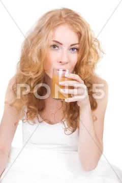 Woman drinking juice in bed Stock Photos