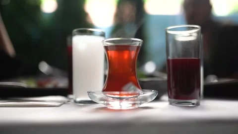 Woman drinking raki at the table with tea in the foreground in a restaurant Stock Footage 180365586