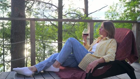 Woman drinking red wine while lying on a sun lounger Stock Footage 282382675