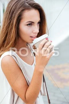 Woman drinking take away coffee while walking on the street Stock Photos