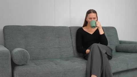 Woman drinking tea or coffee on sofa montage Vidéo 308235053