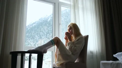 Woman drinking tea sitting by the window overlooking the mountains Stock Footage 163308741