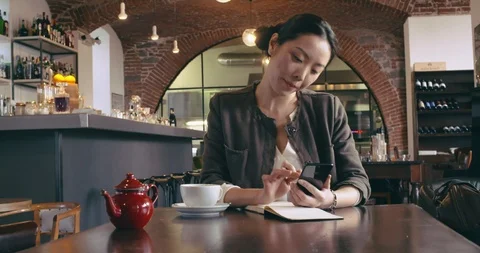Woman drinking tea using smartphone mobile.Front casual dressed asian chinese Video stock 110304651