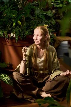 Woman Drinking Tea While Meditating in Home Garden Greenhouse Fotos de archivo