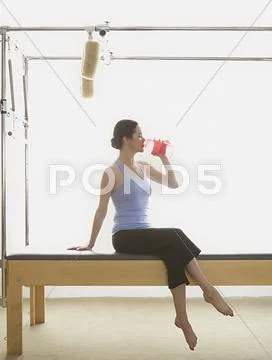 Woman drinking water on exercise equipment Stock Photos