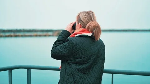 Woman drinks coffee from a cup while standing at the sea in autumn Stock Footage 121553922