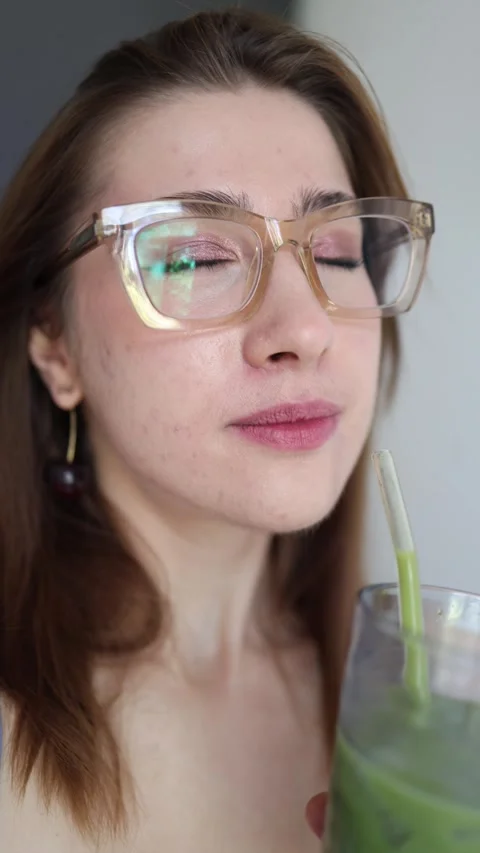 Woman drinks iced matcha through straw and smiles enjoying refreshing taste Видео 342610567
