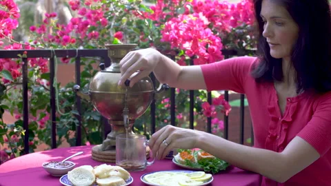 Woman drinks tea from a samovar while sitting a cafe table for lunch Stock Footage 201654294
