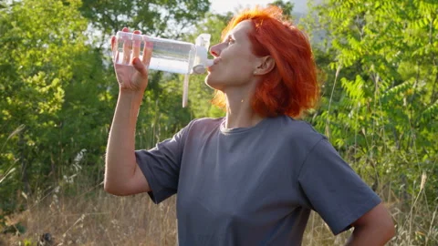 A woman drinks water from a bottle while on a nature walk. Stock Footage 311985709