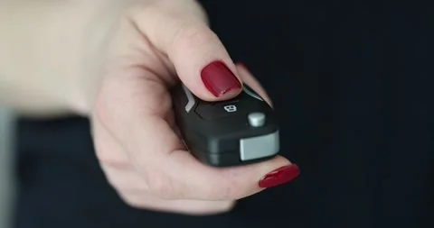 Woman driver presses a button on black car key fob Stock Footage 286193794