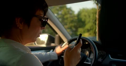 A woman drives while using her phone, showing distractions and safety Stock Footage 314347558