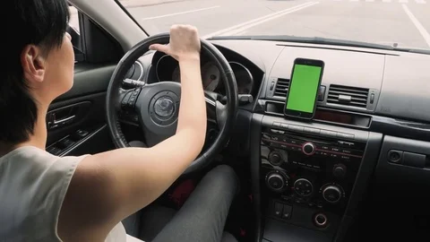A woman is driving a car along a high-speed highway, on the dashboard a phone Stock Footage
