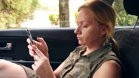 A woman is driving in the car next to the driver and is talking on the phone. 4k Stock Footage