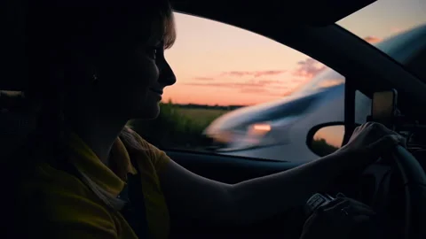 Woman driving car at sunset Stock Footage