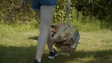 Woman dropping campfire wood bundle beside fire pit, 4k Stock Footage 112763653