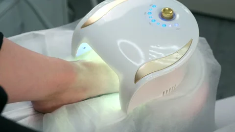 Woman is drying base coal shellac on nails on toes in UV lamp in beauty salon. Video stock 159952530