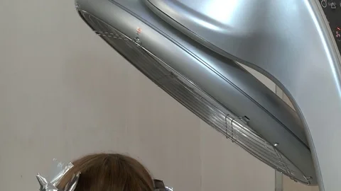 Woman is drying her hair in hair drying machine in salon Stock Footage