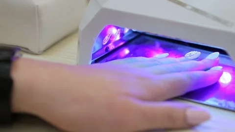 Woman drying nails in special machine in ultraviolet light. Nail salon service. Stock Footage 106405572