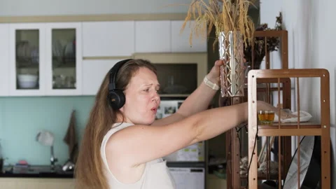 Woman dusts a shelf while dancing along. Stock Footage 309543304