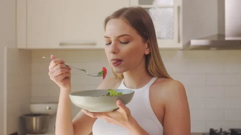 Woman eagerly eats the salad she made herself. The concept of healthy eating Stock Footage 242619257