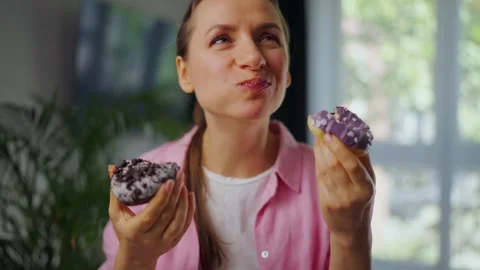 Woman with eating disorder eating two donuts with pleasure and at the same time Video stock 326777053