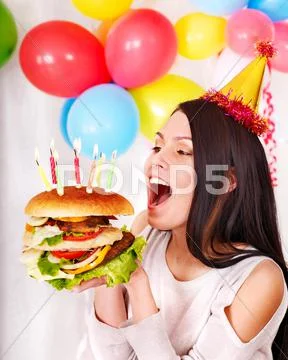 Woman eating hamburger at birthday. Stock Photos