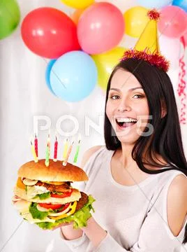 Woman eating hamburger at birthday. Stock Photos