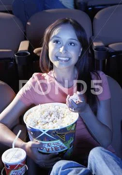Woman Eating Popcorn While Watching Movie In Theater Stock Photos