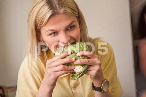 Woman Eating Vegan Burger In Restaurant