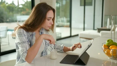 Woman eating yogurt and using laptop Stock Footage 101487520