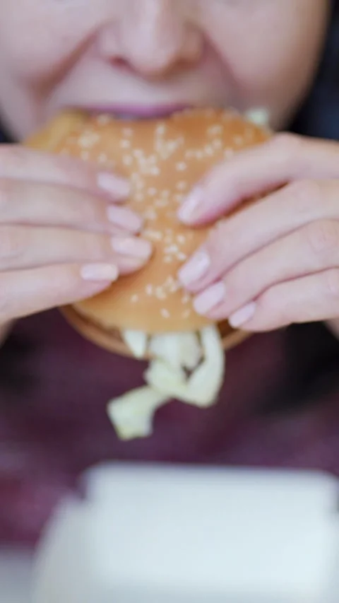 A woman eats a big burger at a fast food restaurant Vidéo 302261377