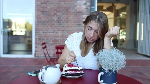 Woman eats cake while having a lively conversation with a friend at cafe Stock-Footage 345028184