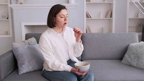 A woman eats chips and her stomach aches. Stock Footage 126267568