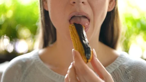 Woman eats chocolate eclair in a cafe close-up Stock Footage 126348670