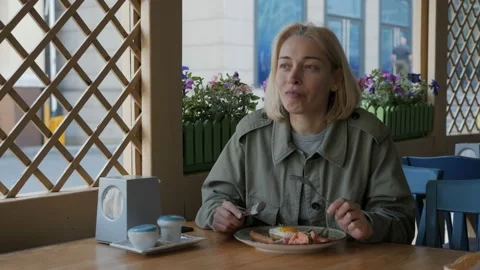 Woman eats eggs for Breakfast, sitting at the terrace cafe Video stock 133196910