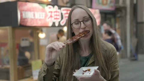 Woman eats glazes kobe beef skewer Stock Footage 231355828