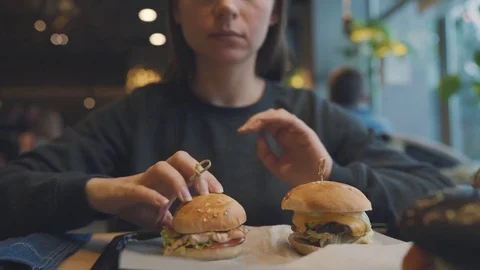 Woman eats a hamburger in a cafe Stock Footage 84797274