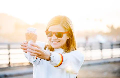 A woman eats ice cream on a pier at sunset Stock Photos