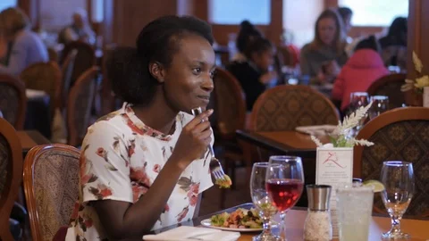 Woman eats  at restaurant laughs while talking eating salad- Stock Footage 89385876