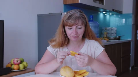 A woman eats a ripe mango, sliced into slices Stock Footage 319319456