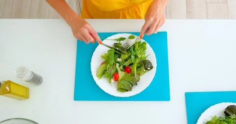 A woman eats a vegetable salad in the dining room at home 库存照片