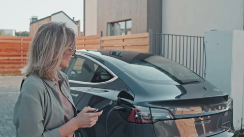 Woman with Electric Car Using Mobile Phone Vidéo 167357370
